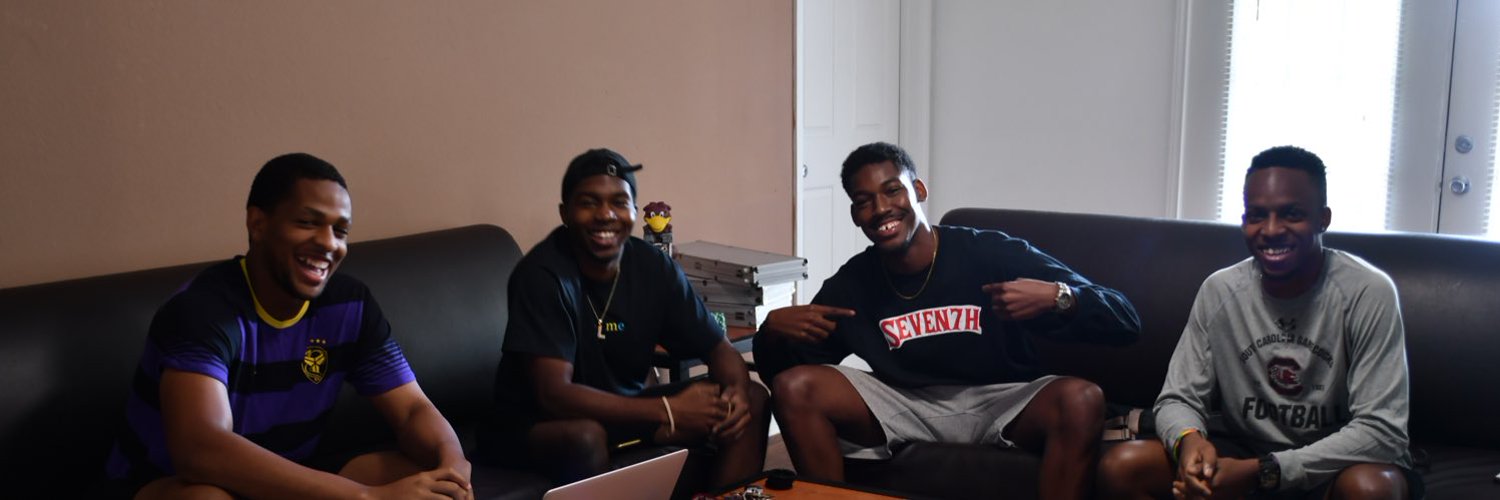 The Dominate The Decade crew laughing together on a couch around a laptop
