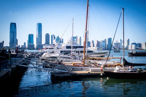 Sailboats fill a marina with a city skyline rising beyond them.